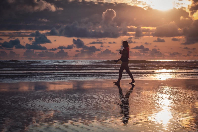 a person walking on a beach at sunset, amanda lilleston, reflecting, bali, profile image