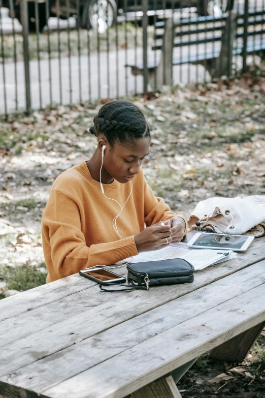 a woman sitting at a picnic table reading a book, pexels contest winner, academic art, black young woman, programming, scribbled, hair styled in a bun