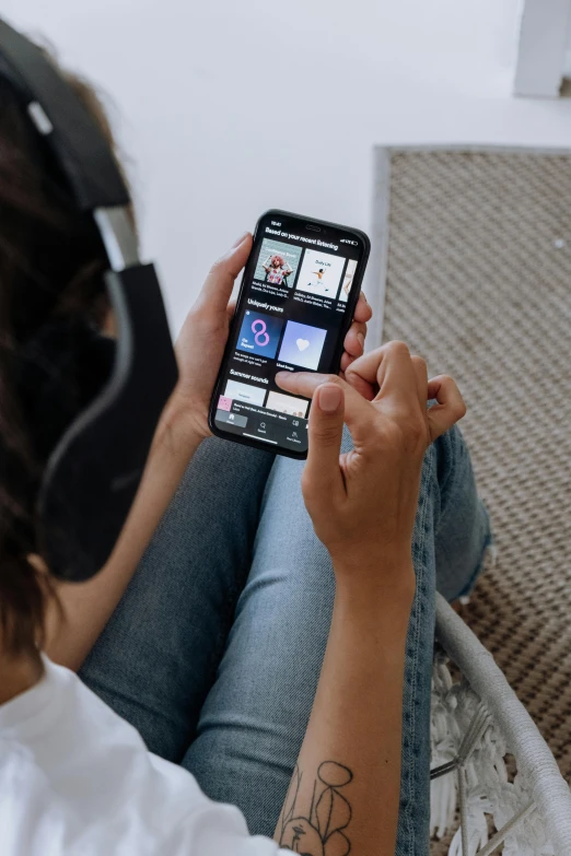 a woman sitting on the floor using a cell phone, an album cover, trending on pexels, everything fits on the screen, detailed product image, wearing black headphones, ( ( theatrical ) )