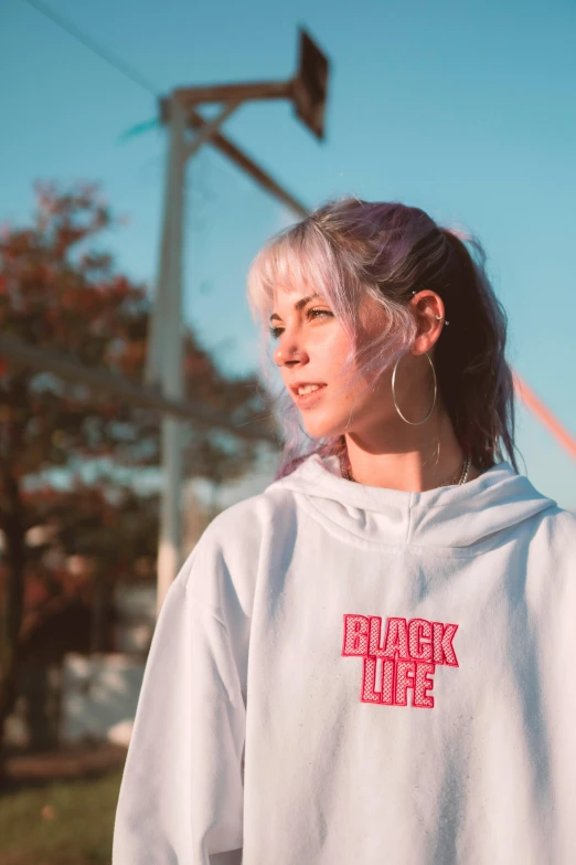 a woman wearing a white hoodie with the words black life on it, an album cover, inspired by Elsa Bleda, unsplash contest winner, realism, black roof, people, bright sky, casual clothing