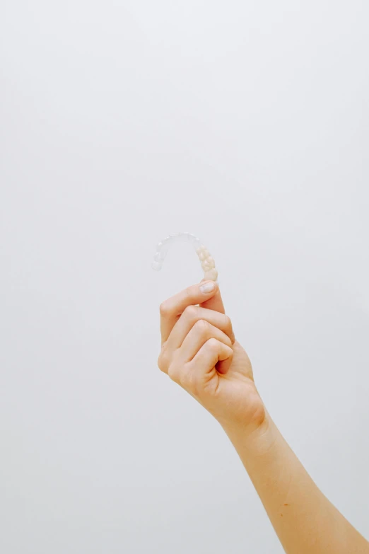 a person holding a toothbrush in their hand, an album cover, by Nicolette Macnamara, trending on pexels, translucent white skin, ring, 15081959 21121991 01012000 4k, ear