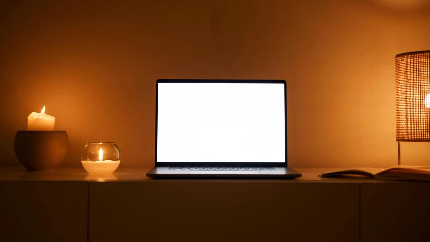 a laptop computer sitting on top of a table, inspired by Elsa Bleda, computer art, candle, white space in middle, vanilla - colored lighting, orange lighting