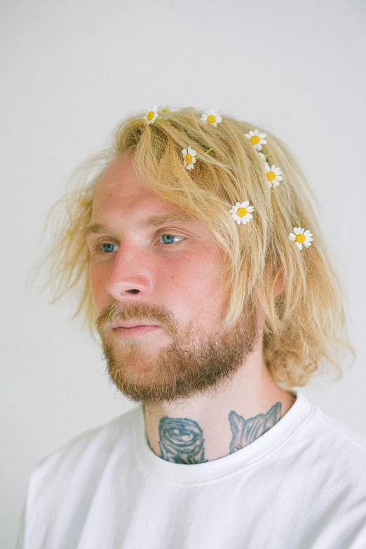 a man with a flower in his hair, inspired by Lasar Segall, featured on reddit, aestheticism, messy blonde hair, daisies, an all white human, facial tattoos