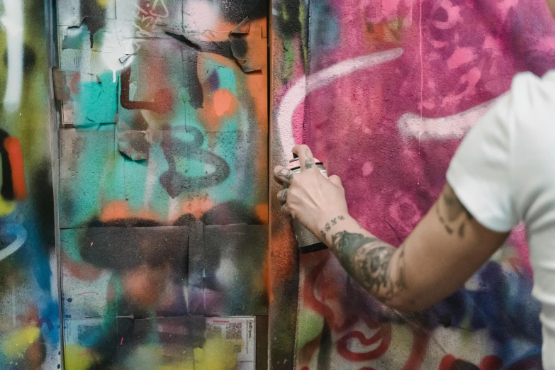 a man spray painting graffiti on a wall, by Tom Bonson, pexels contest winner, graffiti, lil peep, hand painted textures on model, lush, tattoo parlor photo