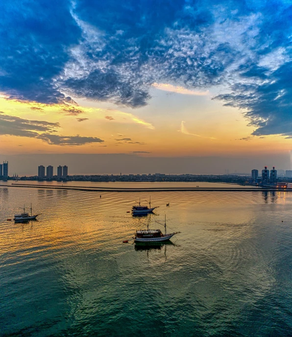 a group of boats floating on top of a body of water, by Robbie Trevino, pexels contest winner, karachi skyline background, magic hour photography, today\'s featured photograph 4k, panorama