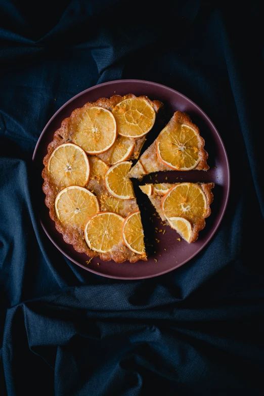 a piece of pie sitting on top of a purple plate, oranges, in front of a black background, thumbnail, birdseye view