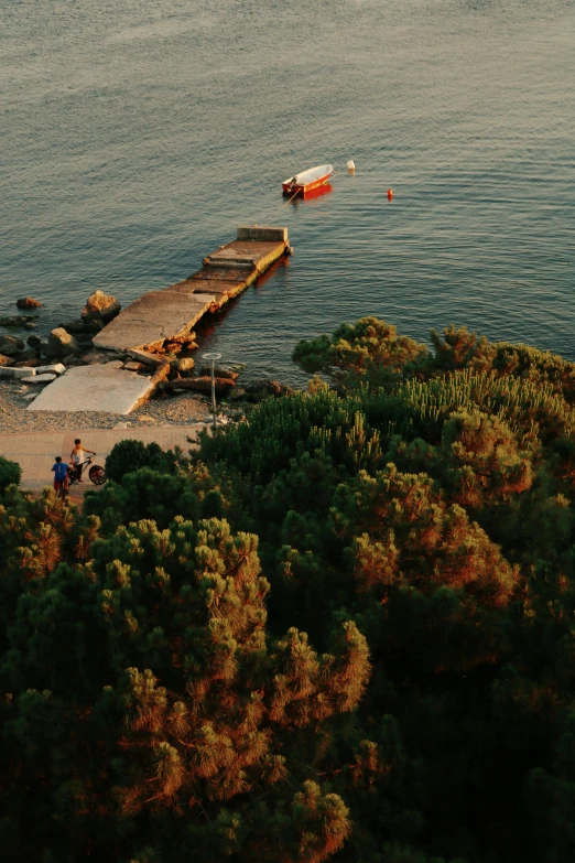 a boat sitting on top of a body of water, black sea, which shows a beach at sunset, a high angle shot, small dock