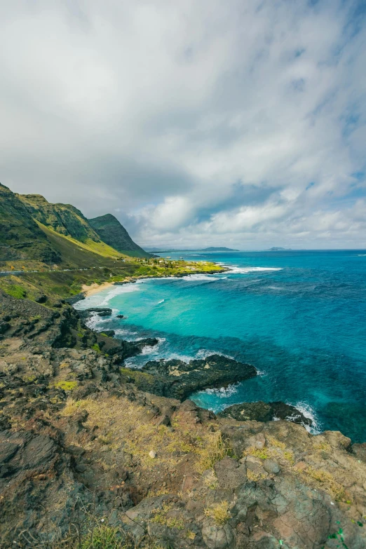 a large body of water next to a lush green hillside, by Adam Manyoki, unsplash, hawaii beach, square, 8 k hi - res, rocky hills