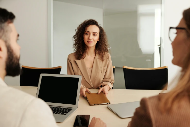 a group of people sitting around a table with laptops, by Emma Andijewska, pexels contest winner, girl in a suit, in a meeting room, brown, slightly minimal