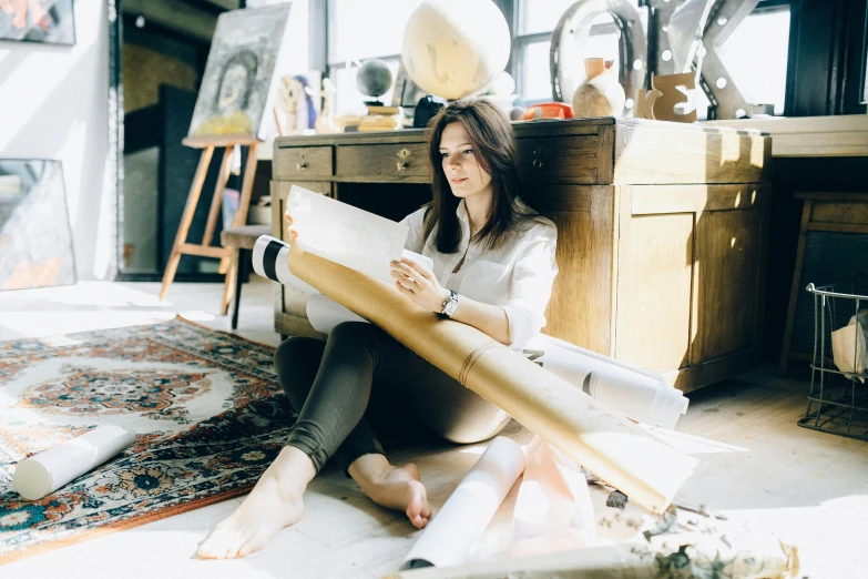 a woman sitting on the floor reading a book, pexels contest winner, arbeitsrat für kunst, rivuletpaper art, rugs, promotional image, in a workshop