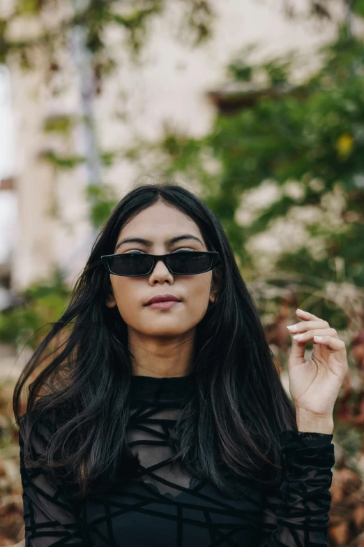 a woman in a black dress and sunglasses, trending on pexels, south east asian with long, streetwear, blackhair, non binary model