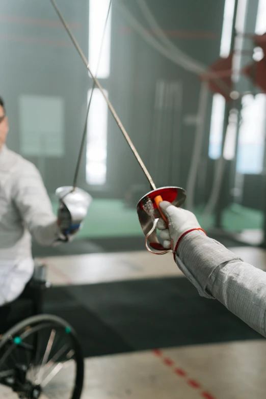 a man in a wheelchair holding a sword next to a woman in a wheelchair, pexels contest winner, fencing, glossy surface, thumbnail, fist training