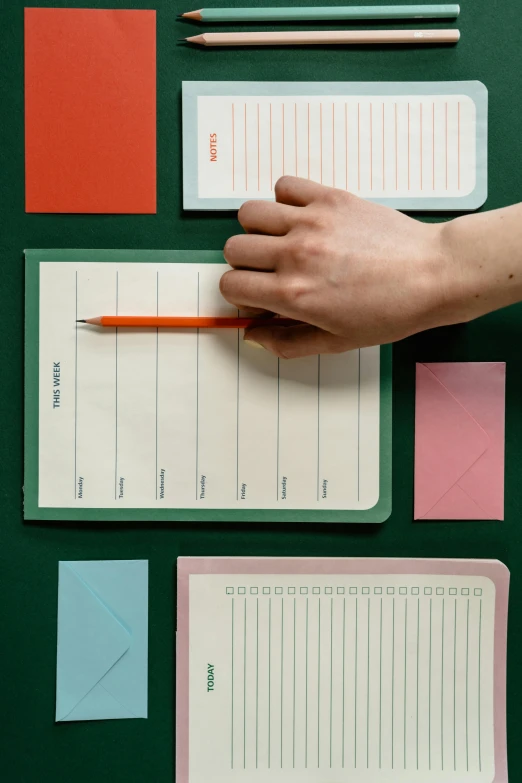 a person writing on a piece of paper with a pencil, an album cover, green and pink colour palette, wes anderson style, ui card, full product shot