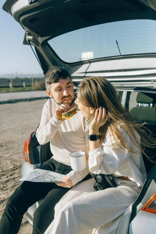 a man and woman sitting in the trunk of a car, trending on pexels, eating outside, 🚿🗝📝