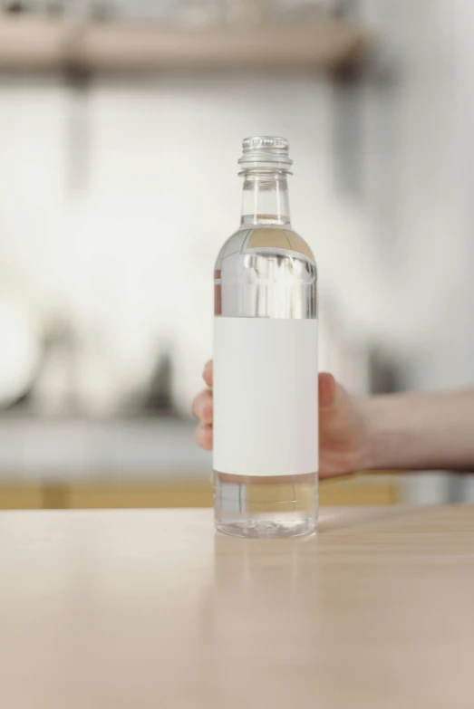 a person holding a bottle of water on a table, a picture, no - text no - logo, product label, large, without text