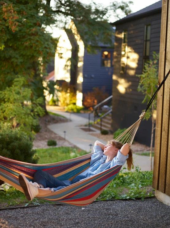 a woman laying in a hammock in a yard, dwell, woodstock, profile image, exterior shot