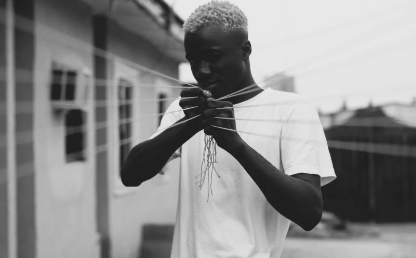 a black and white photo of a man tying a tie, by Emma Andijewska, pexels contest winner, realism, white hair dreads, handsome hip hop young black man, arms made out of spaghetti, with short bobbed white hair