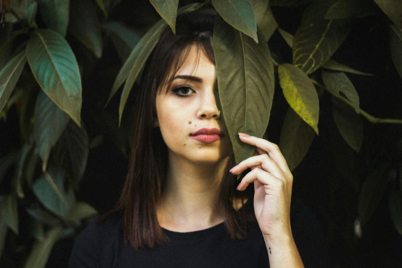 a woman holding a leaf in front of her face, inspired by Elsa Bleda, pexels contest winner, realism, portrait emily ratajkowski, lush surroundings, perfect face symmetry, portrait of vanessa morgan