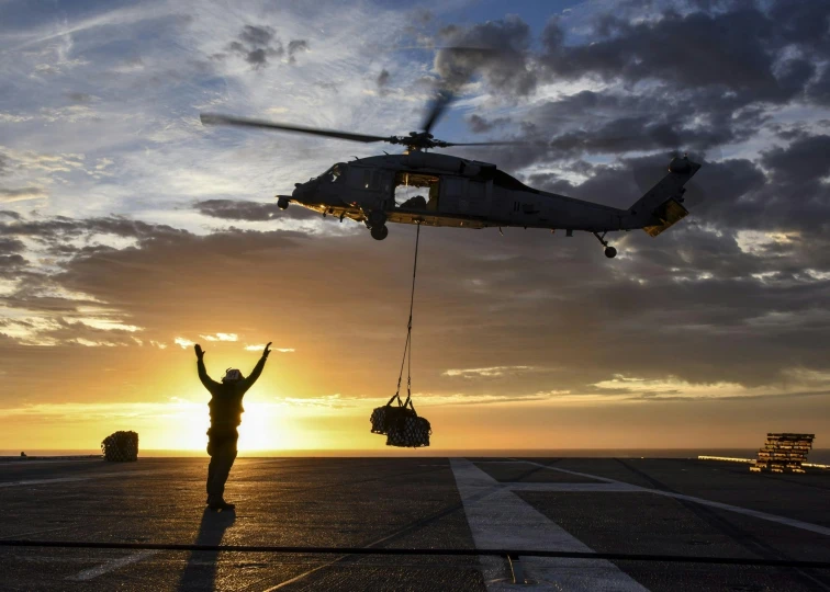 a helicopter that is flying in the sky, by John Murdoch, happening, standing on a ship deck, sun set, airforce gear, photograph of the year