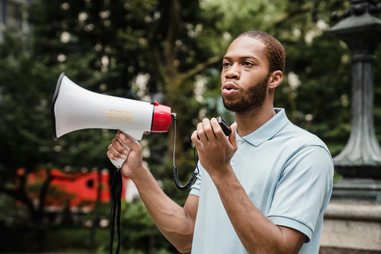 a man holding a white and red megaphone, by Julia Pishtar, pexels contest winner, jemal shabazz, young adult male, 🚿🗝📝