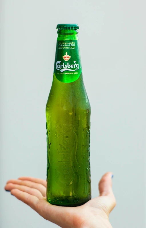 a person holding a bottle of beer in their hand, caroline gariba, extra crisp image, green, surface with beer-texture