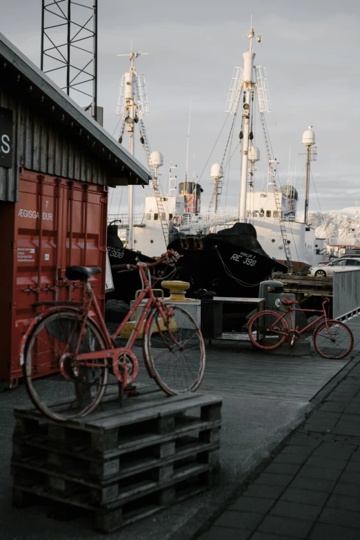 a couple of bikes parked next to a building, shipping docks, reykjavik, fishing boats, snacks