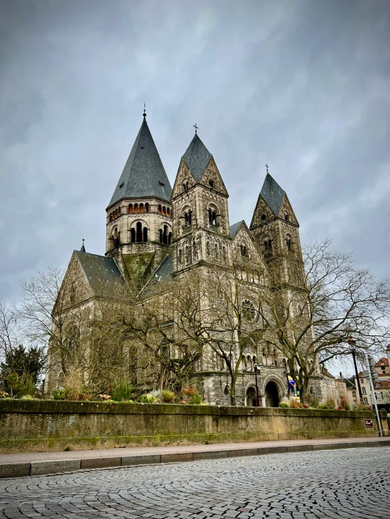 a large church sitting on the side of a road, inspired by Rainer Maria Latzke, romanesque, in a city with a rich history, gloomy skies, 🚿🗝📝, preserved historical