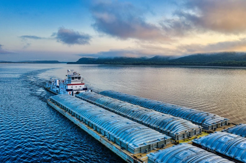 a large boat sitting on top of a body of water, by Greg Spalenka, pexels contest winner, refrigerated storage facility, quebec, morning atmosphere, farming