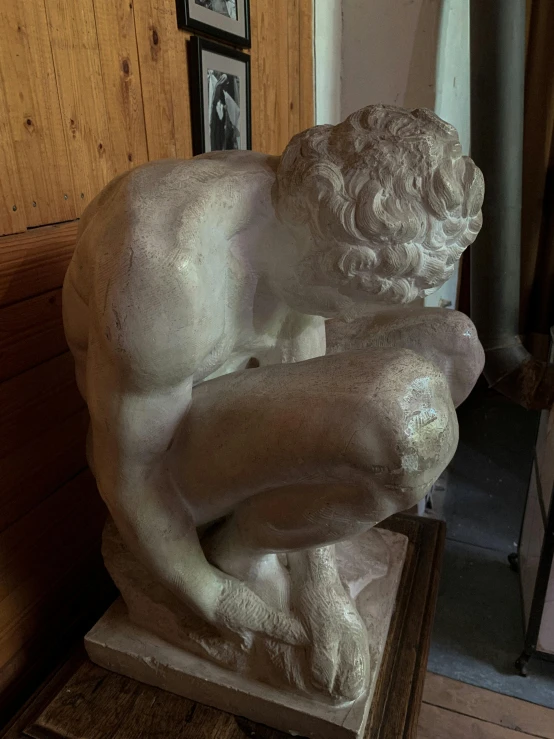 a statue of a man sitting on top of a wooden table, inside a marble, they are crouching, michelangelo style, 155 cm tall