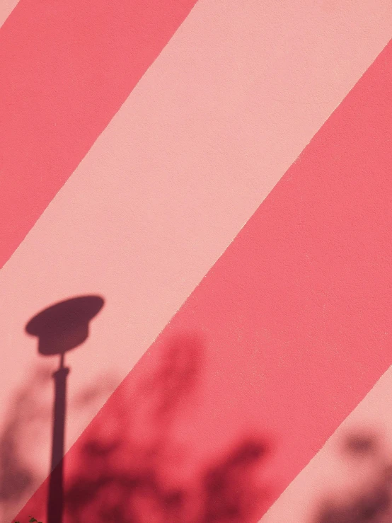 a street light in front of a pink and white striped wall, an album cover, trending on unsplash, red tint, website banner, grainy footage, billboard image