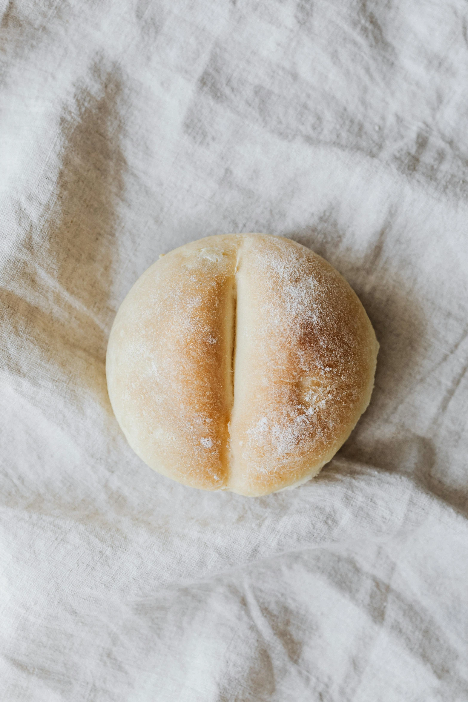 a loaf of bread sitting on top of a white cloth, a portrait, unsplash, sleek round shapes, 3/4 front view, italian, bao phan