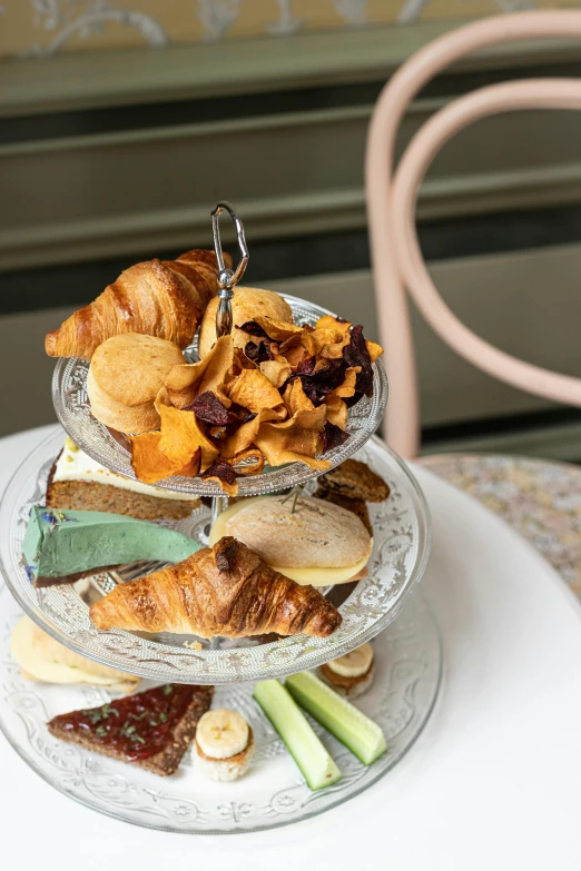 a three tiered tray of food sitting on top of a table, inspired by Richmond Barthé, art nouveau, dog eating croissants in paris, plated arm, organic detail, award - winning