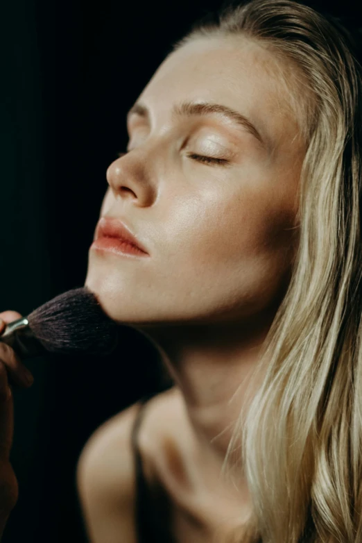 a woman brushes her face with a brush, inspired by Elsa Bleda, trending on pexels, hyperrealism, close up of a blonde woman, smelling good, sexy lips :5 stylish, portrait soft low light