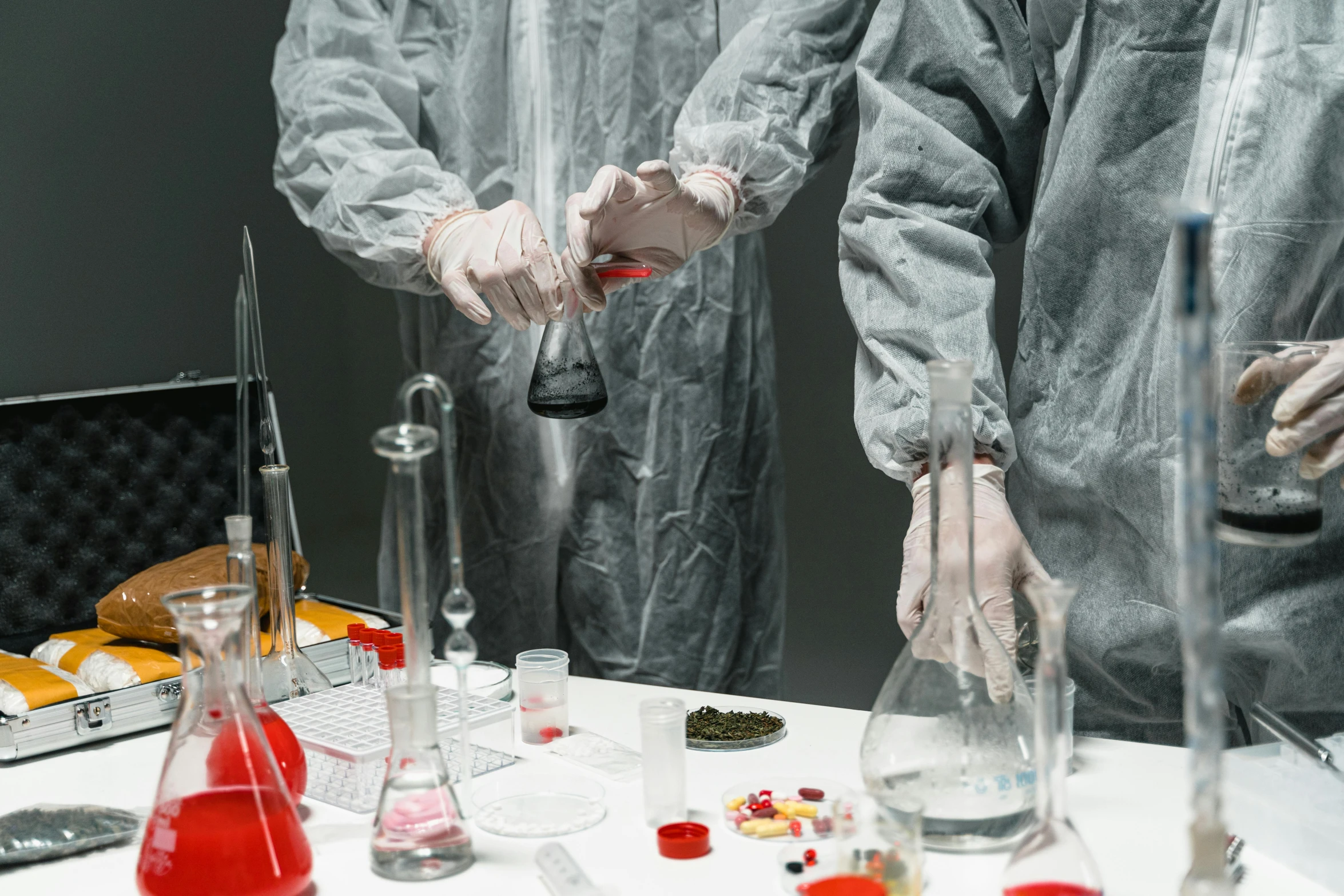 a couple of people that are standing in front of a table, pexels contest winner, process art, russian lab experiment, taking mind altering drugs, wearing long silver robes, handling laboratory equipment