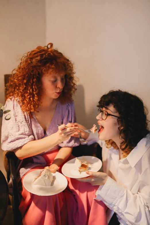 two women sitting at a table with plates of food, an album cover, inspired by Nan Goldin, trending on pexels, renaissance, red curly hair, eating cakes, high quality photo, transparent