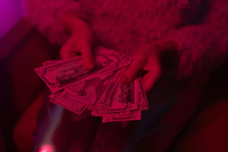 a person holding a bunch of money in their hand, inspired by Elsa Bleda, pexels contest winner, visual art, neon pink, red room, bella poarch, concert