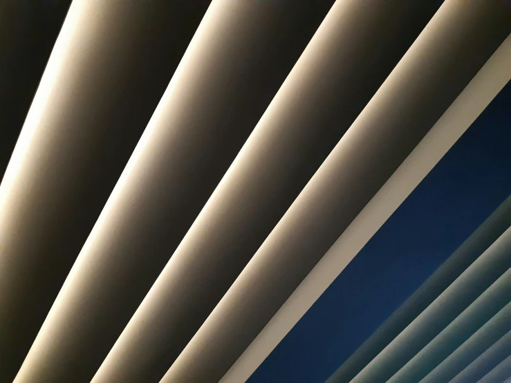 a clock mounted to the side of a building, by Carey Morris, unsplash, light and space, soft light through blinds, sky made of ceiling panels, in a row, blue and grey