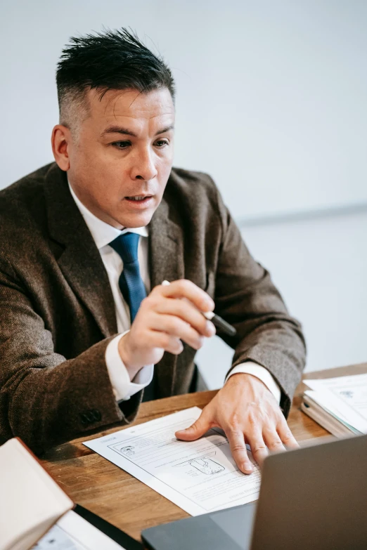 a man sitting at a table in front of a laptop computer, lawyer clothing, thumbnail, 2019 trending photo, in a classroom