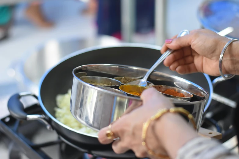 a person stirring food in a pot on a stove, inspired by John Steuart Curry, pexels contest winner, community celebration, caulfield, stainless steel, intricate detail and quality