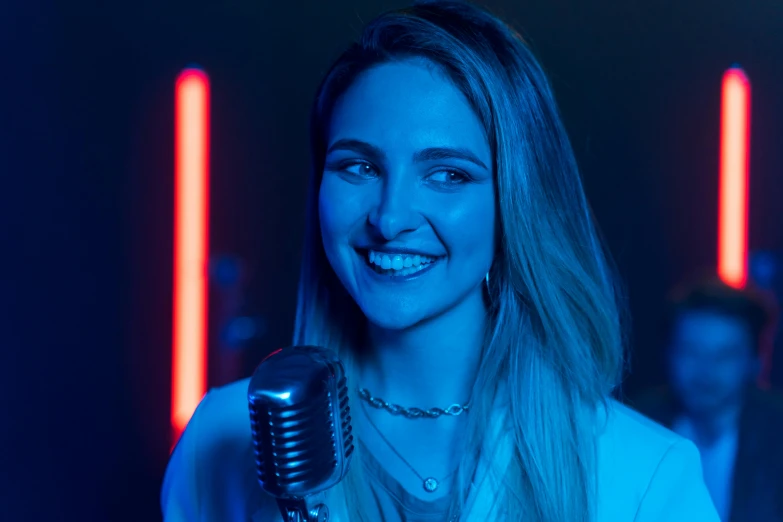 a woman holding a microphone in front of a group of people, blue and red lights, smiling young woman, pokimane, avatar image