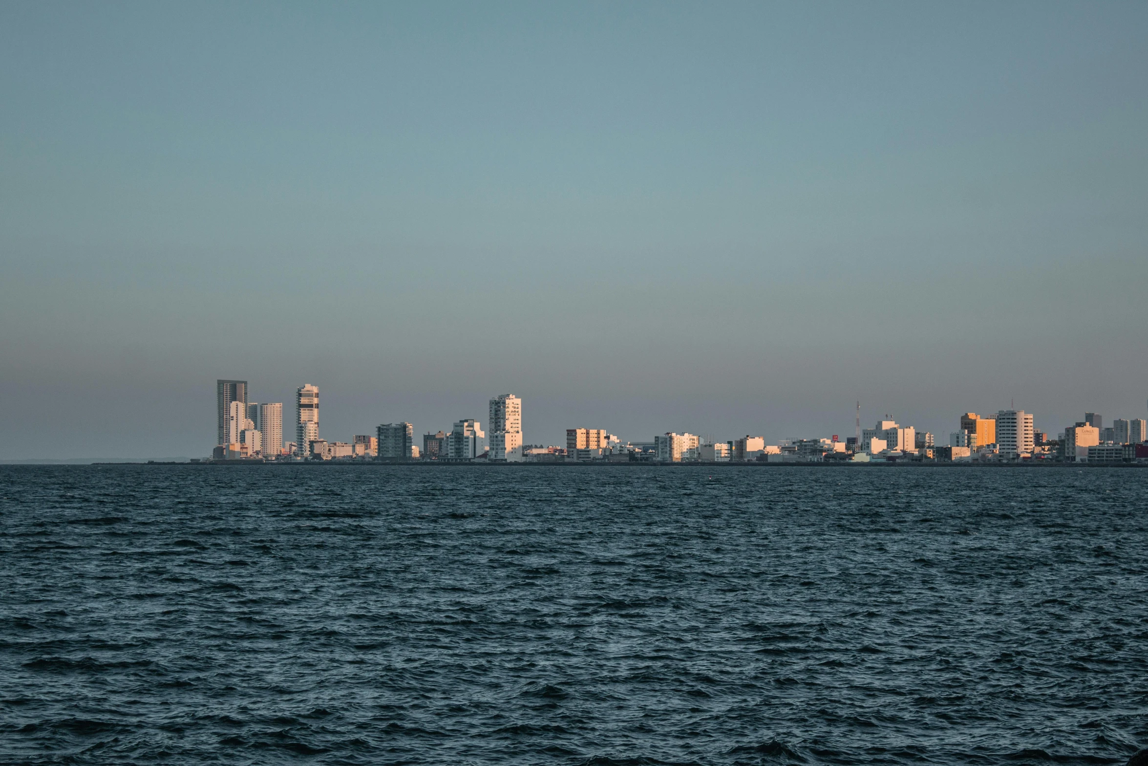 a large body of water with a city in the background, pexels contest winner, gulf, late afternoon, viewed from the ocean, florida