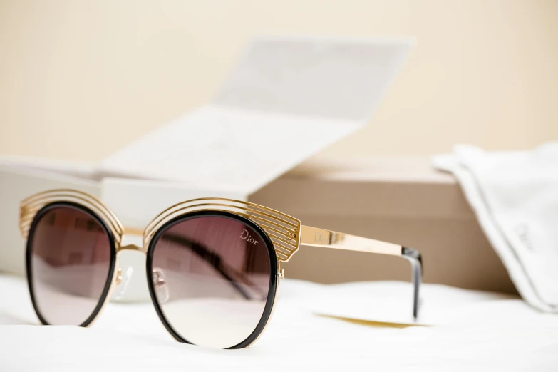 a pair of sunglasses sitting on top of a bed, oscar de la renta, gold detailed line work, inside its box, thumbnail