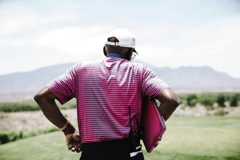 a man standing on top of a lush green field, lebron james solemn at tea party, golf digest, pink and red color scheme, shot from the back