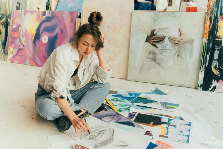 a woman sitting on the floor drawing on a piece of paper, a photorealistic painting, trending on pexels, process art, trending on pinterest，maximalist, ouchh and and innate studio, artist wearing overalls, colourful artwork