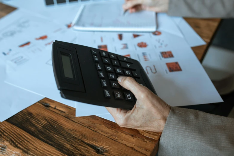 a close up of a person using a calculator, a picture, pexels contest winner, sitting on top a table, 15081959 21121991 01012000 4k, realistic », corporate business