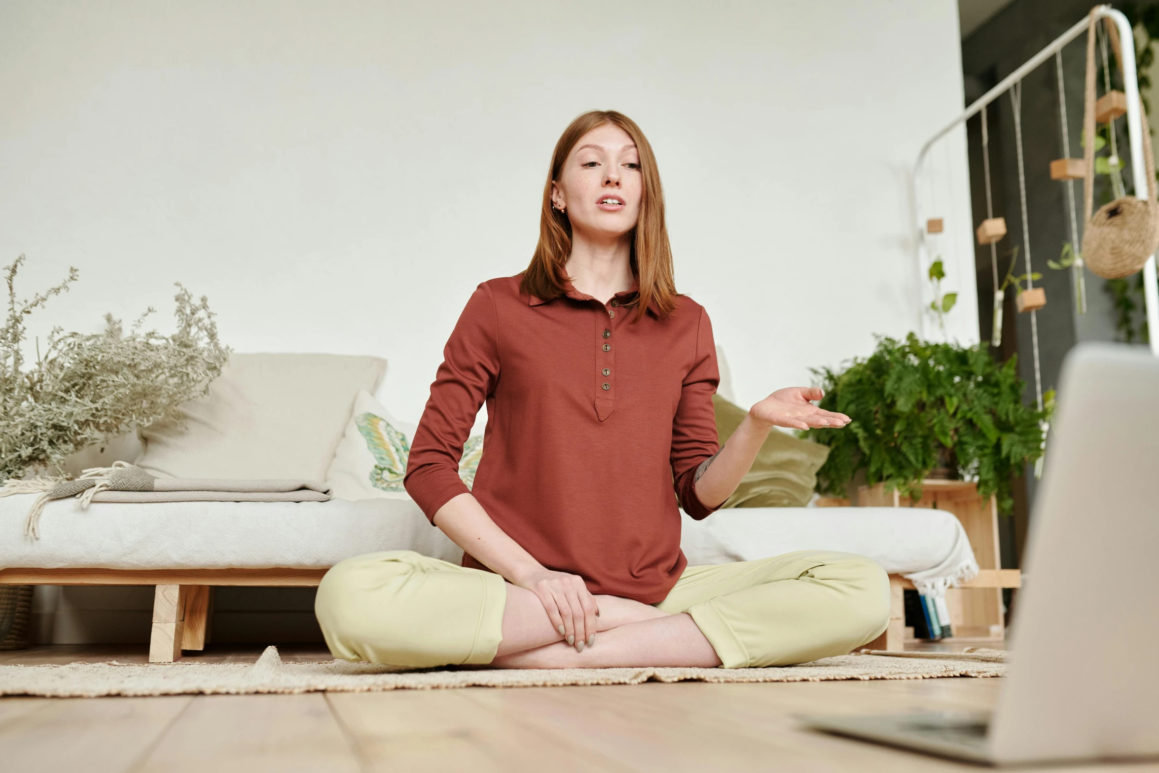 a woman sitting on the floor in front of a laptop, inspired by Caro Niederer, renaissance, red shirt brown pants, sukhasana, sitting on the sofa, wearing a tracksuit