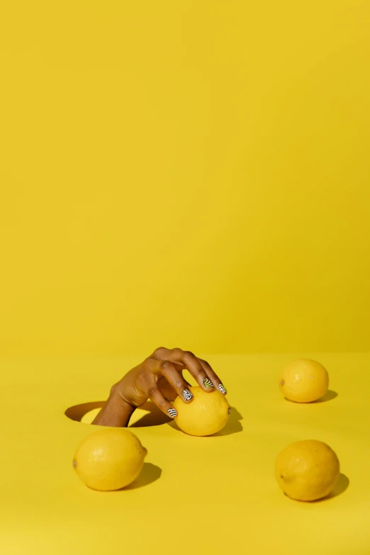 a person reaching for lemons on a yellow surface, by Doug Ohlson, aida muluneh, full frame image, vivid)