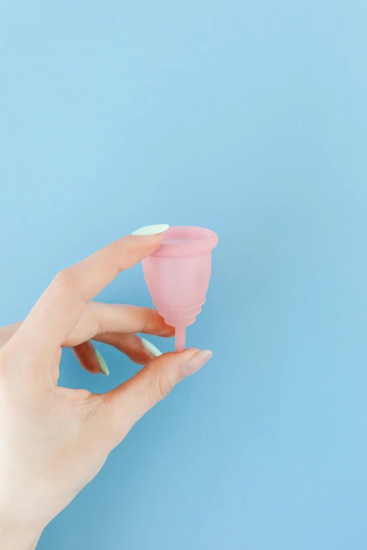 a woman's hand holding a pink cup on a blue background, plasticien, 14mm, long pointy pink nose, silicone cover, smol