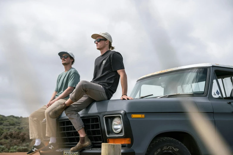 two men sitting on the hood of a truck, a portrait, unsplash, wearing a fisher 🧥, dusty and smokey, angled shot, dustin lefevre