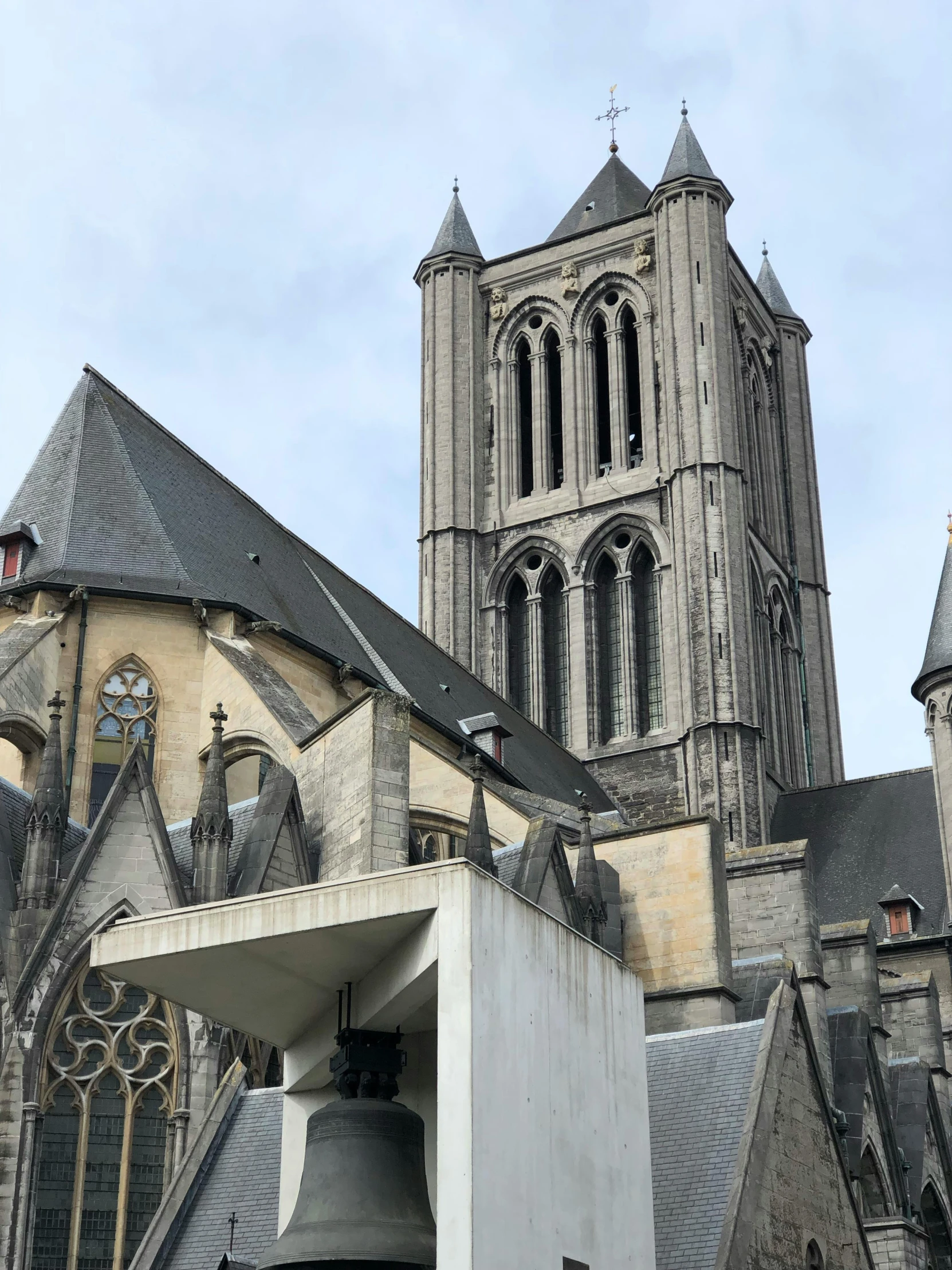 a tall building with a bell in front of it, an album cover, by Philip de Koninck, unsplash, romanesque, brutalist appearance, cathedral in the background, opposite the lift-shaft, overview